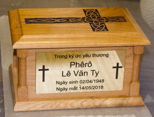 An oak ash casket with a lasered top and an extra plaque on the side