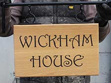 Wooden sign with wrought iron hanging bracket.