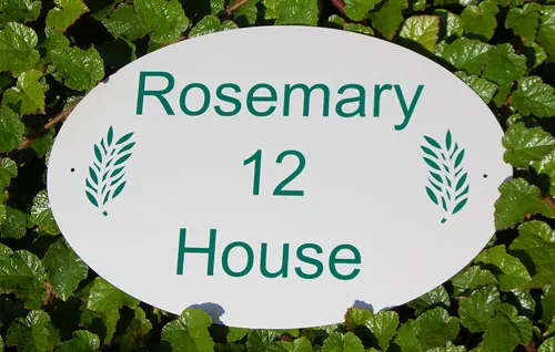 White oval house sign with green lettering