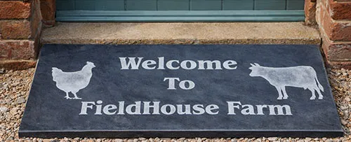 This doorstep was unpainted. Engraved slate doorstep Welcome to FieldHouse Farm with sandblasted lettering and farm animal motifs
