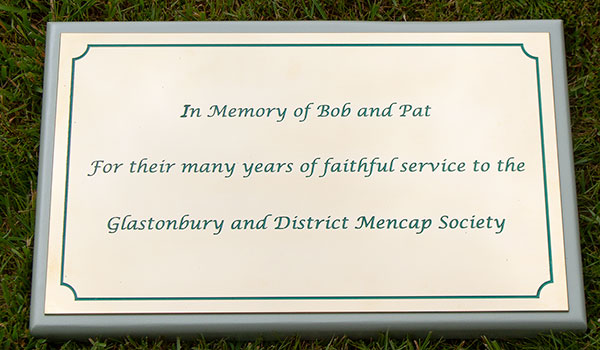 Brass plaque with green text on a hardwood backing boards painted lichen green.