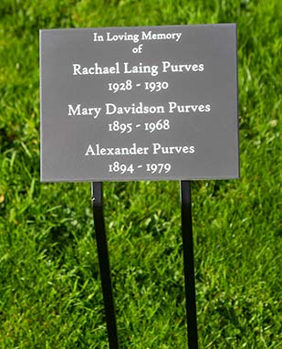 Engraved memorial fixed to metal plate with double angled spikes.