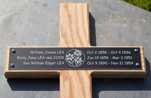 black memorial plaque on oak cross