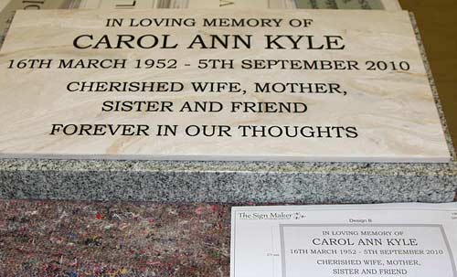 Engraved marble corian plaque fixed to a silver grey granite wedge