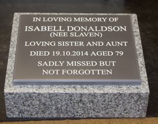 Engraved corian plaque on granite plinth.