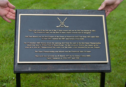 Framed metal stand holding brown granite backing board with bronze plaque attached.