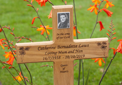 Black and white porcelain plaque on an engraved wooden cross.